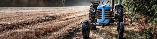 Old tractor in a field on a summer morning with the sun coming u